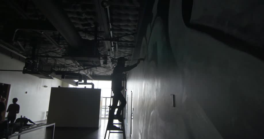A man is painting a wall from a ladder