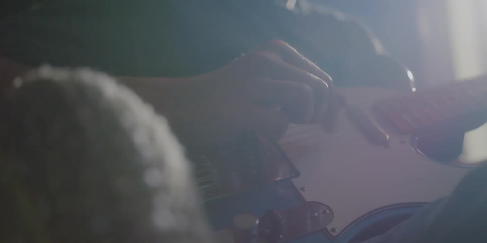 Musician sits and plays electric guitar
