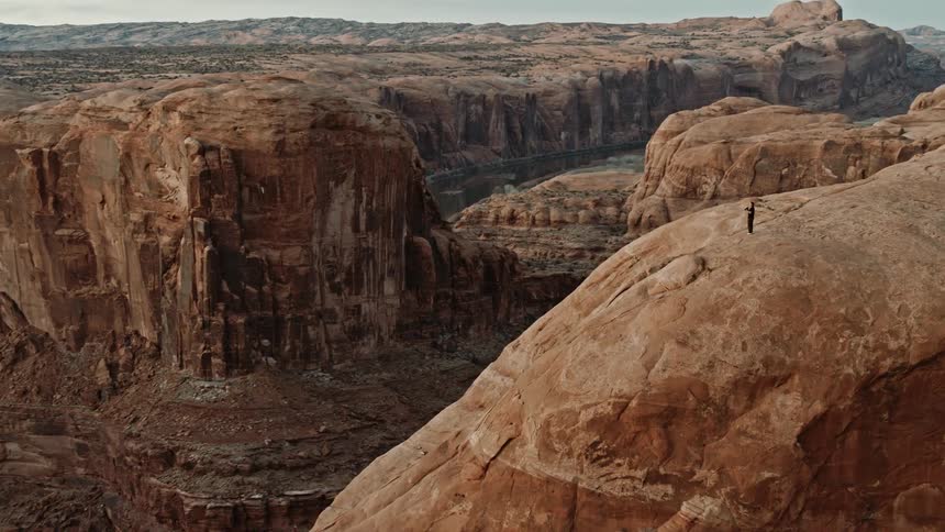 An adventurer photographs a large canyon at dusk