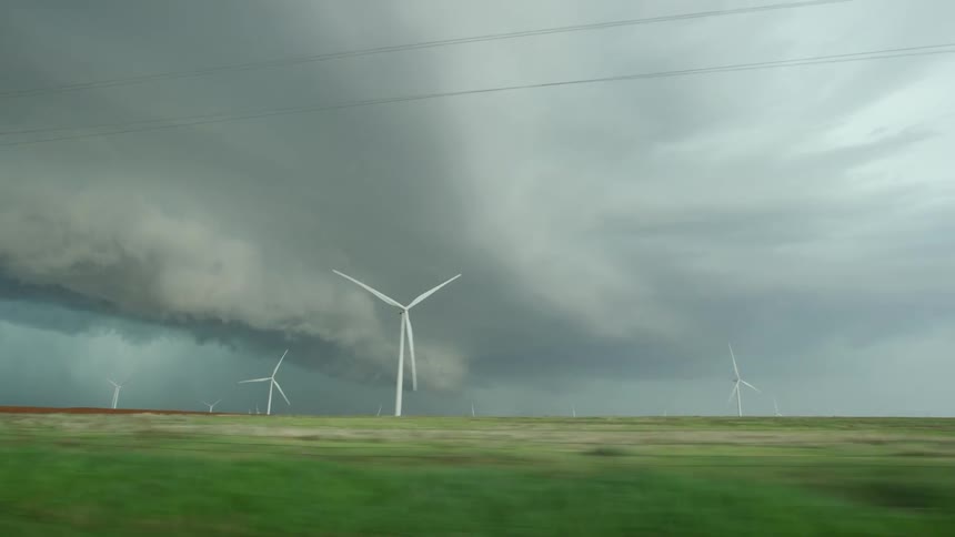 Wind mills and wind turbines spin as a shelf cloud and severe thunderstorm pound the rural farm land deep in the bread basket of the United States