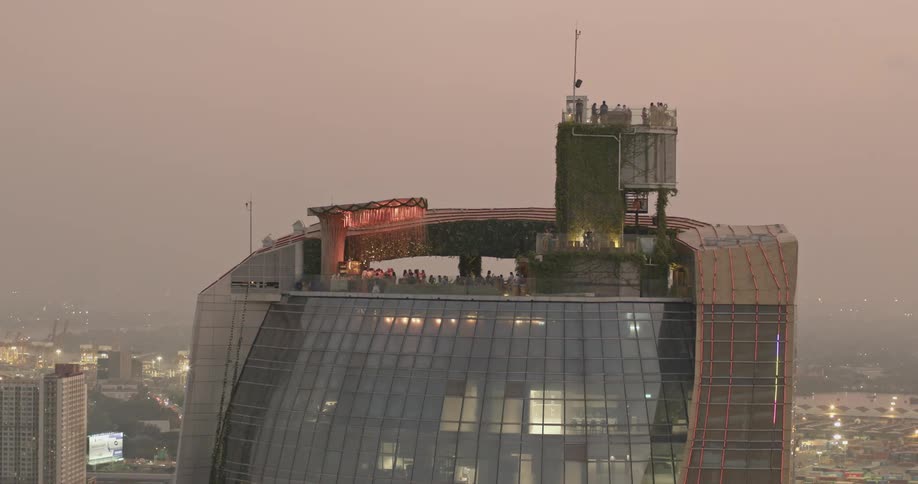 People mingle on roof of skyscraper under red tinted sky on foggy day