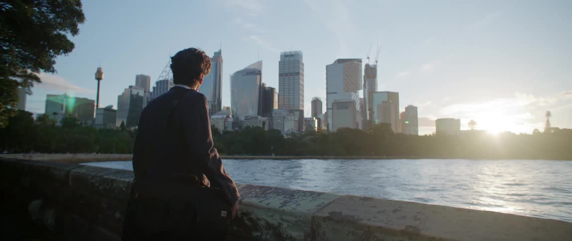 A man looks over the water towards the city