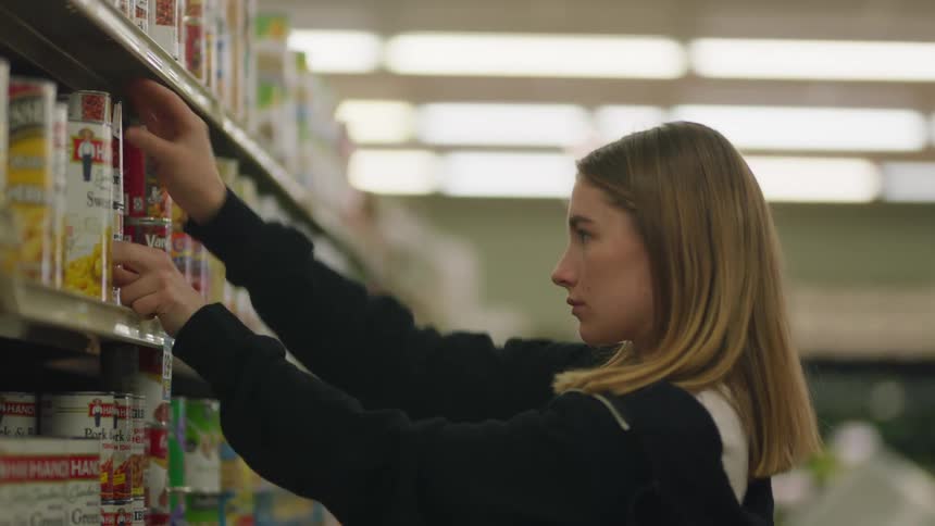 A woman putting cans on a shelf