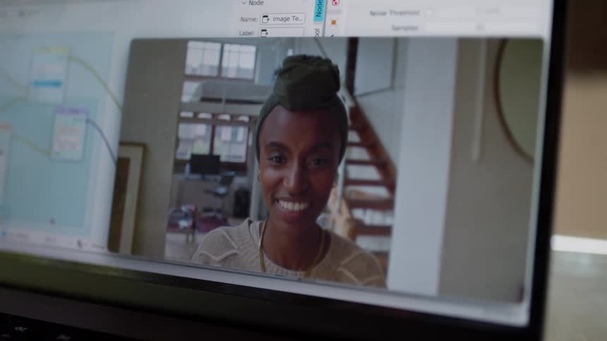 A woman waves and talks on the laptop
