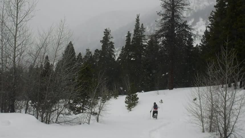 A person is hiking downhill as it snows