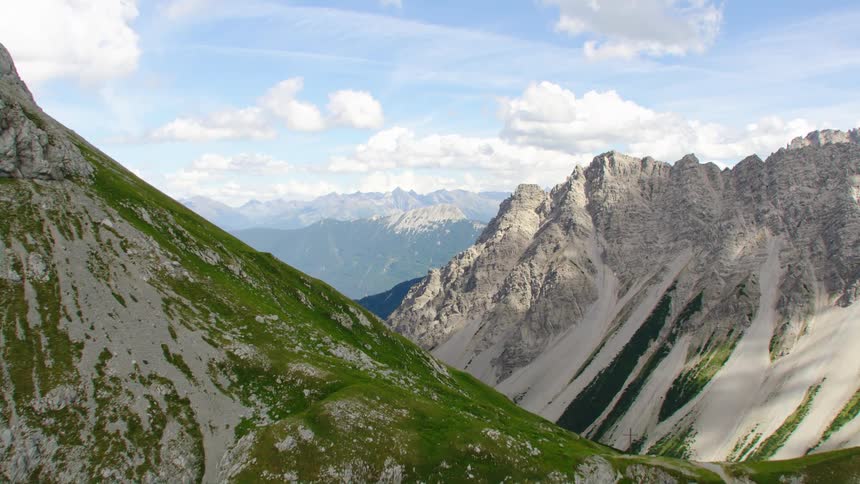 A stone mountain range with patches of grass on its slopes