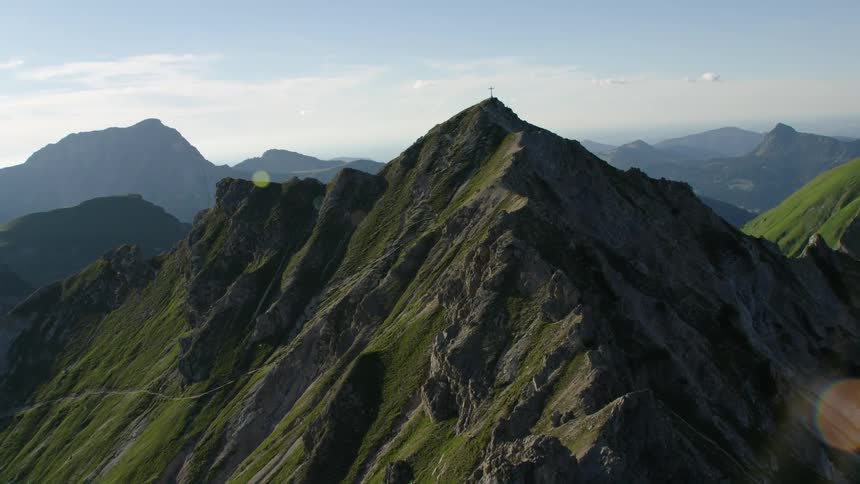 Wisting aerial view of a cross atop the summit of a mountain range at morning