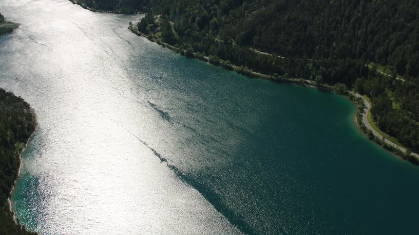The sun glitters on lake plansee next to mountain