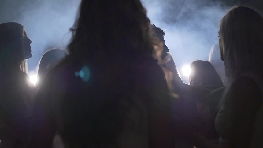 A man in a foggy room is surrounded by women