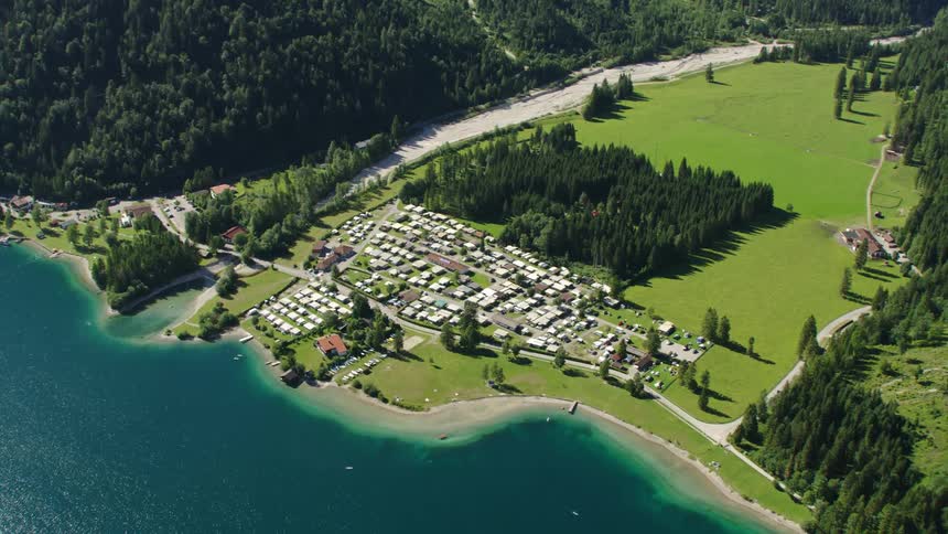 Aerial view of coastal town next to mountain with forest