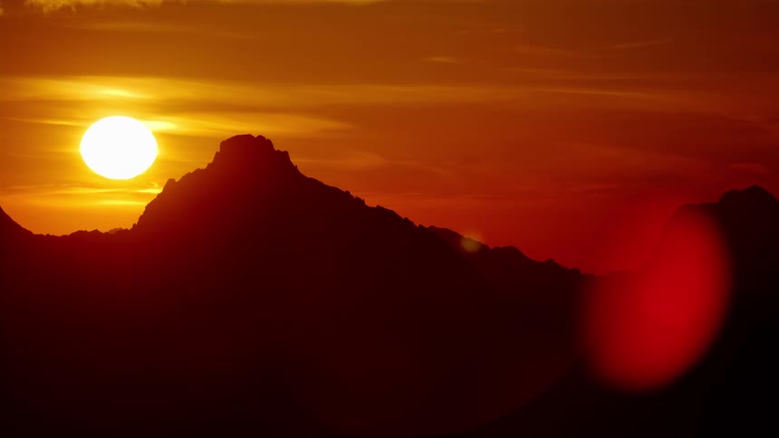 Aerial view of mountain peaks silhouetted against the shining sun