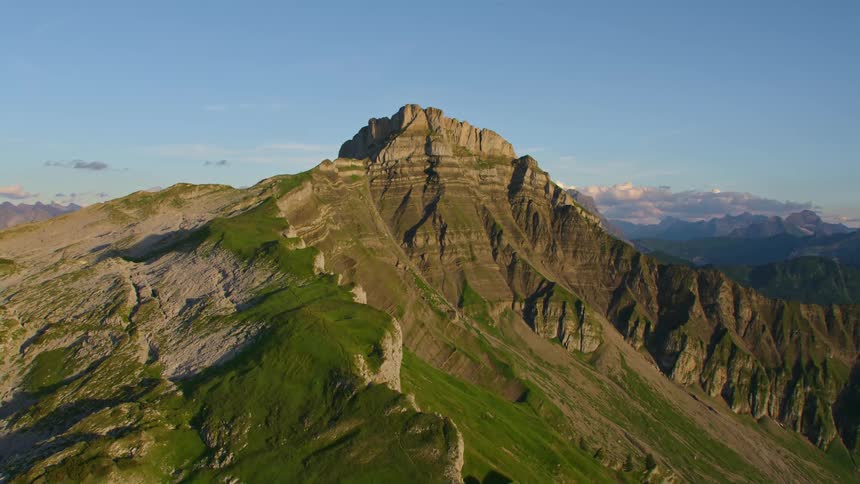 The summit of a mountain within an expansive mountain rang can be seen in aerial footage