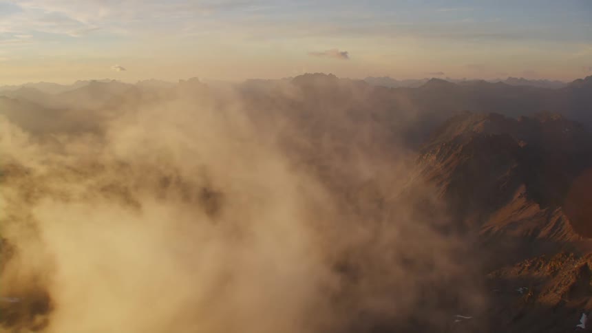Aerial view of clouds floating over mountains at sunset