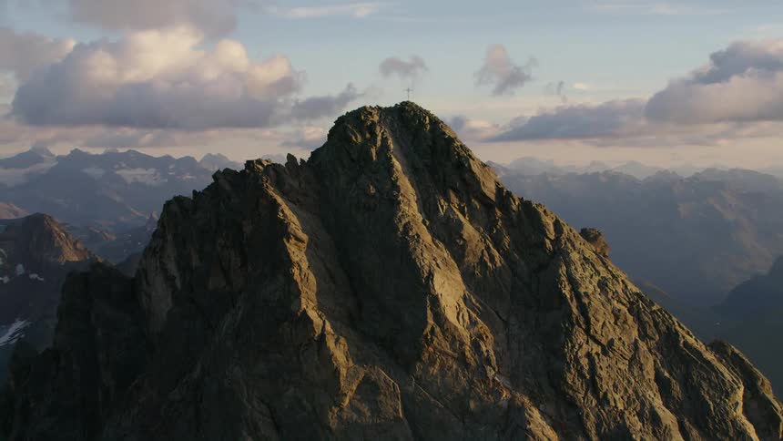A jagged stone mountain peak under a daytime sky