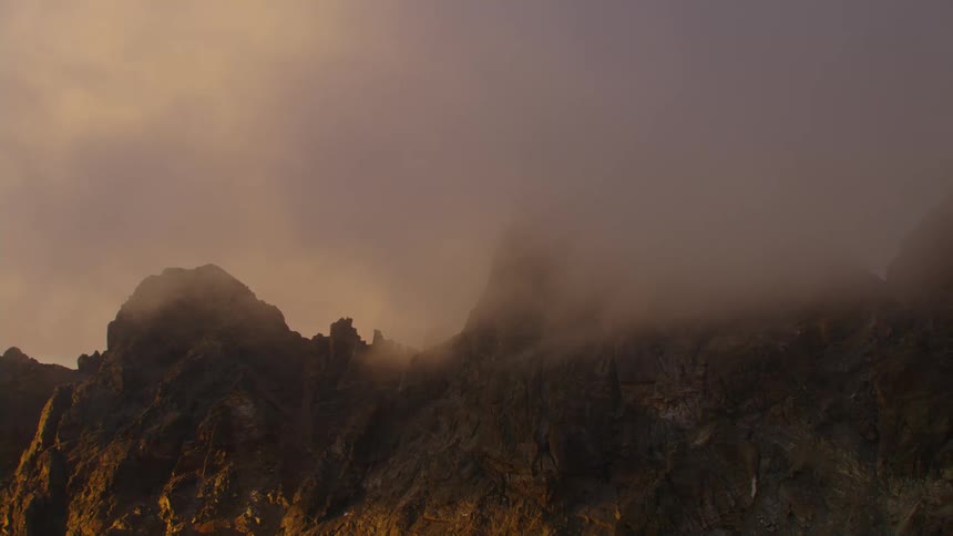 Aerial view of floating clouds over steep mountains