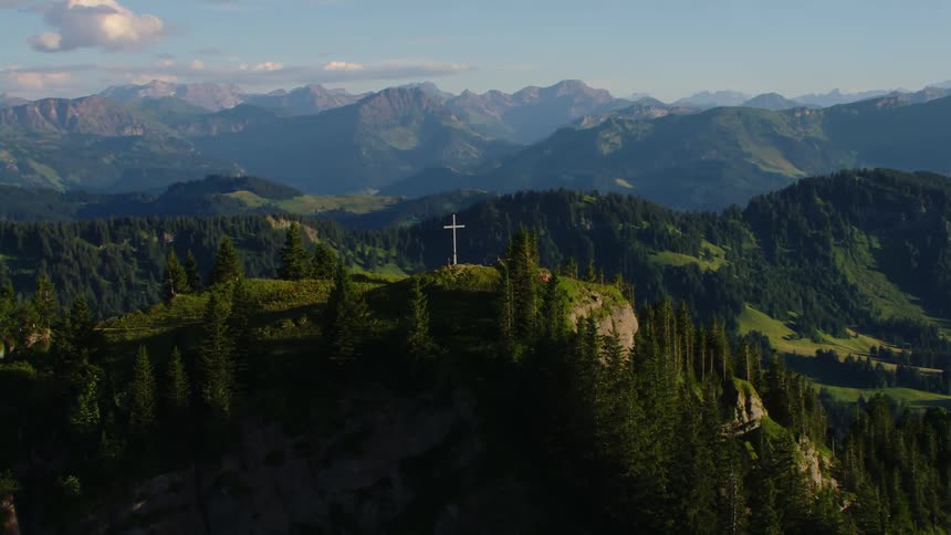 Aerial view of a cross atop the summit of a mountain range at morning