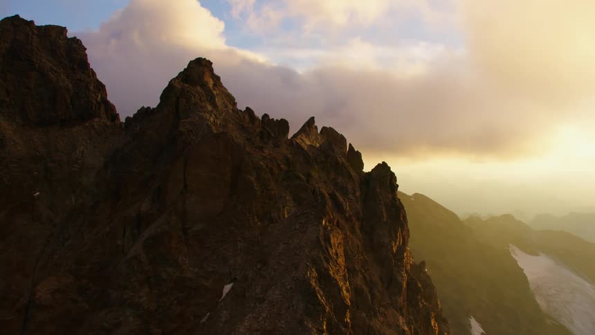 Aerial view of steep mountain peak under clouds