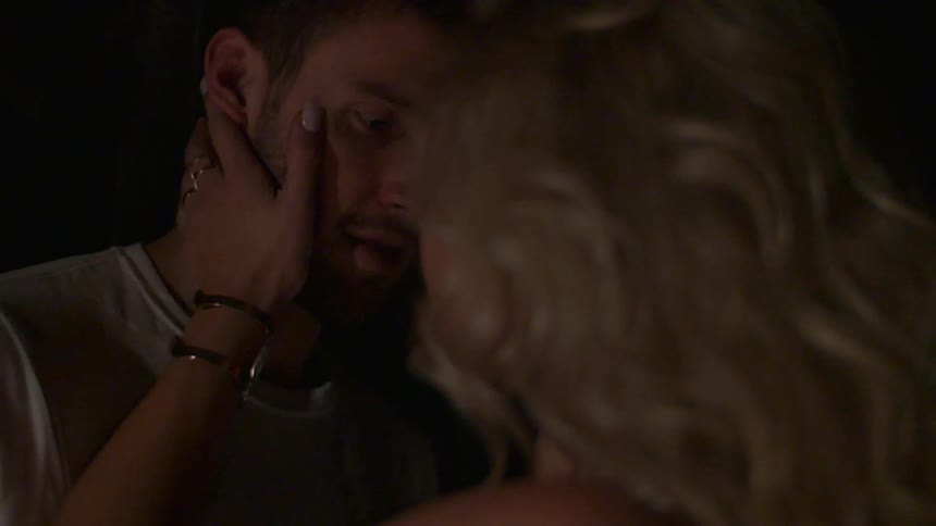 A woman touches a man's face while pulling him close