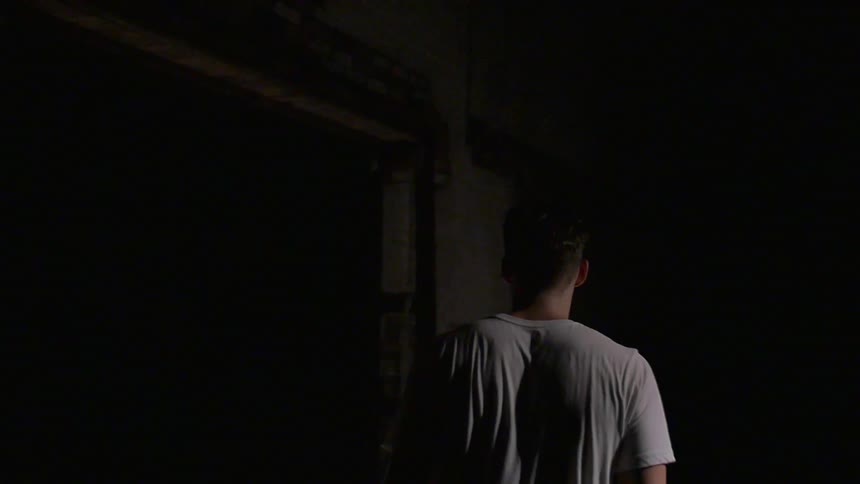A man is walking towards a woman seated under a spot light