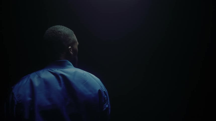 A man turns around while standing in a dark room
