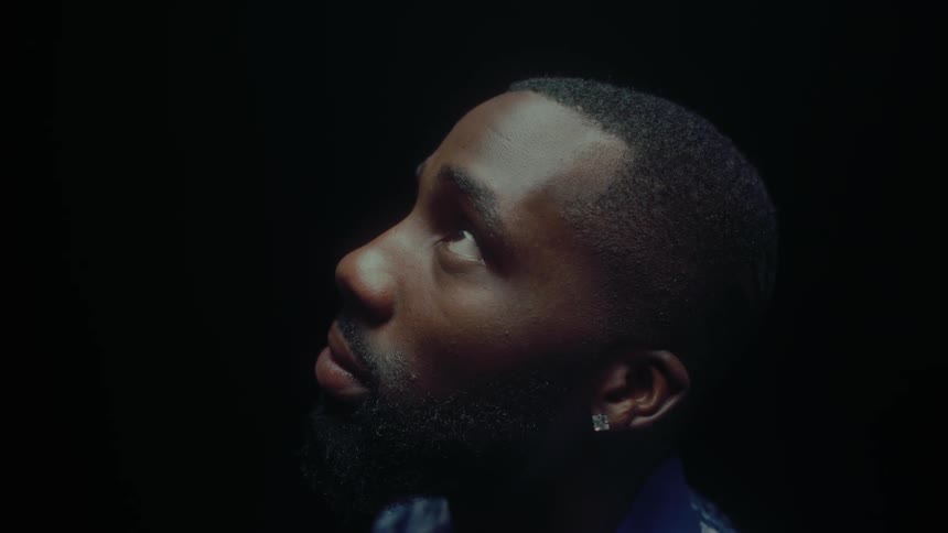 A black man stands still while staring at something that is above him