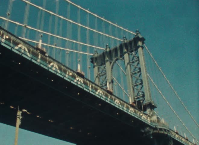 Light glints along cables of suspension bridge under a clear blue sky