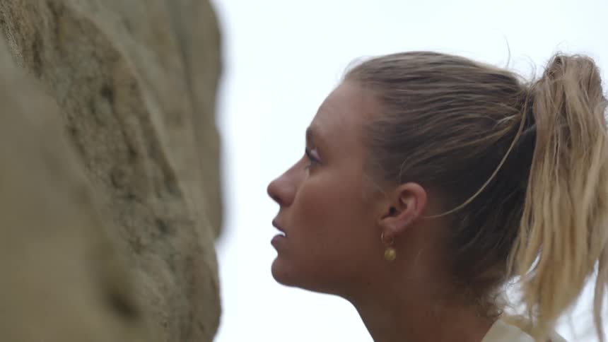 A woman climbs up the side of a mountain