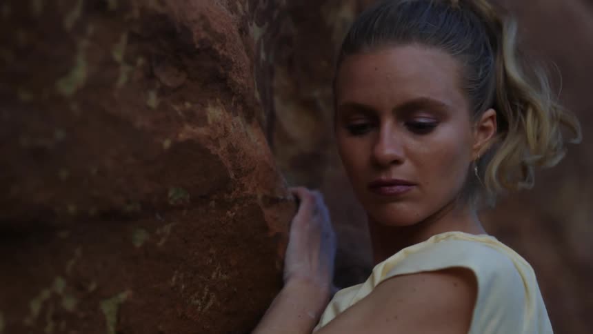 A woman climbs a natural rock face with her hands and feet during the day