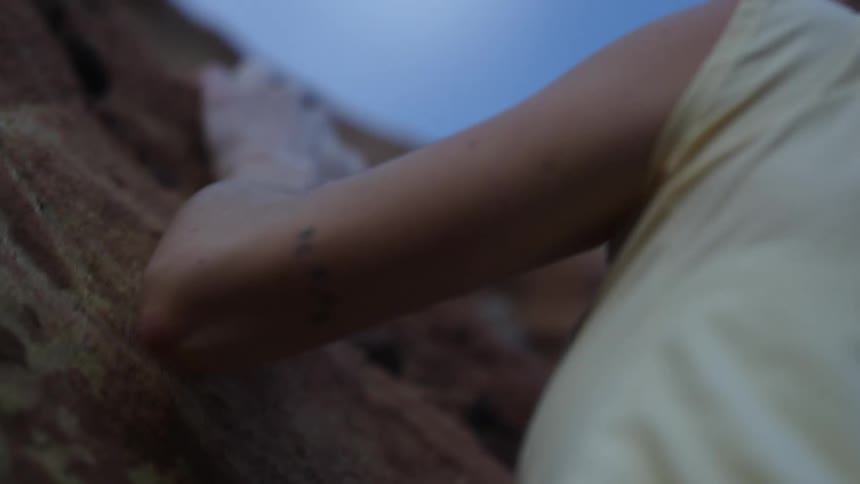 A woman free climbs up the side of a mountain