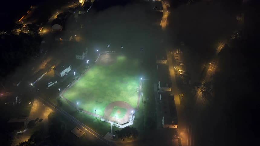 Traffic drives past a sports stadium with a baseball field