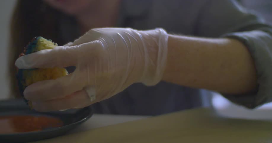 A woman dips a sponge in paint and then applies it to a piece of paper