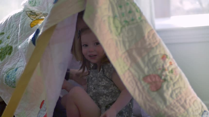 A girl and women are in a blanket tent together