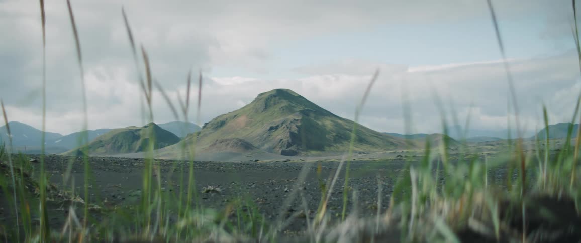 A man starts running through a dirt field toward a mountain