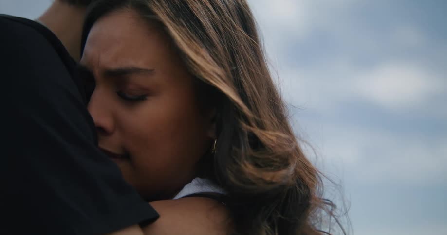 A couple is hugging each other in the middle of the day outside