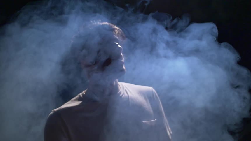 A man looks around surrounded by smoke