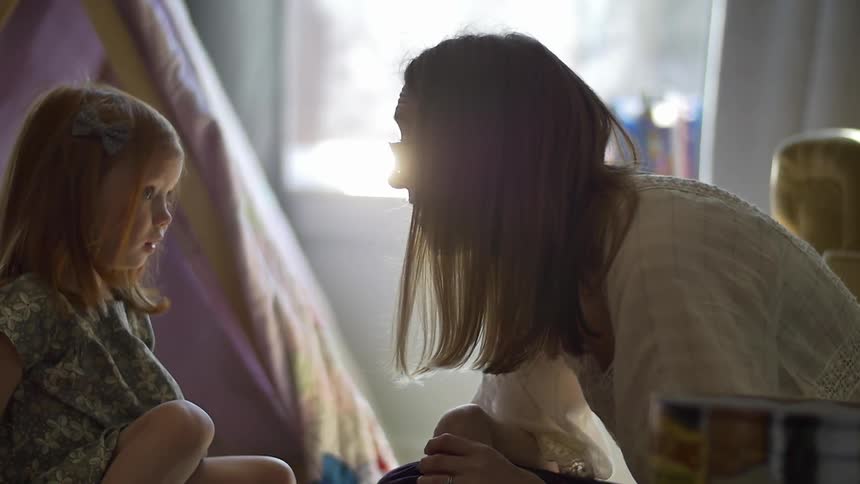 A woman and girl talk together on the floor