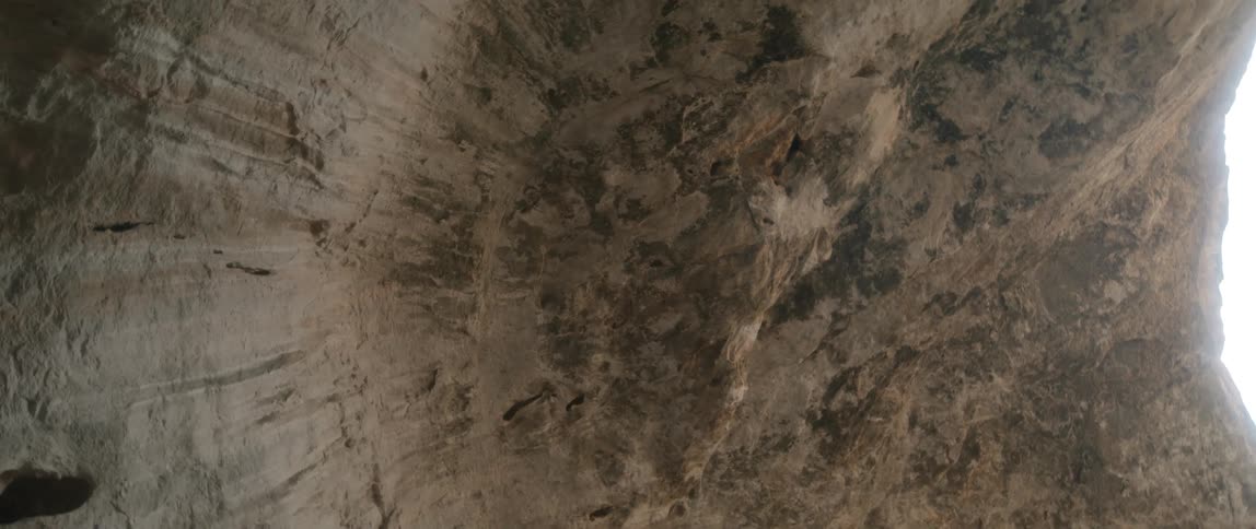 A rock canyon wall with daylight above