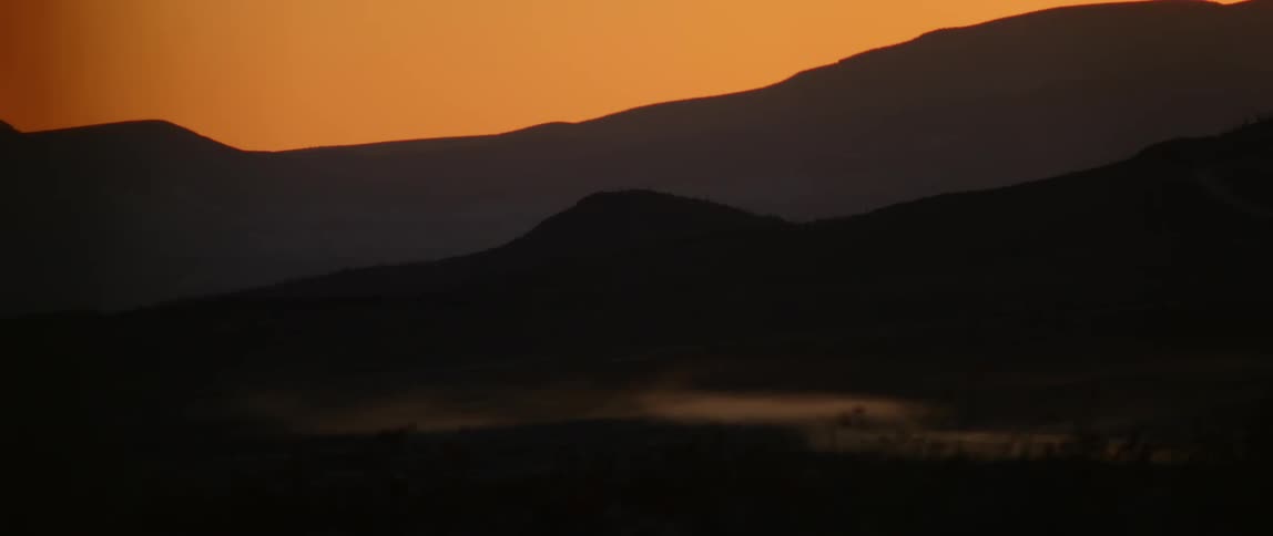 The sun sets over a vast mountain range