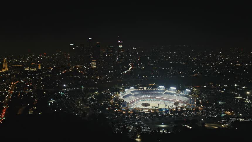 A packed sports stadium in downtown Los Angeles is lit up by fireworks in the night sky