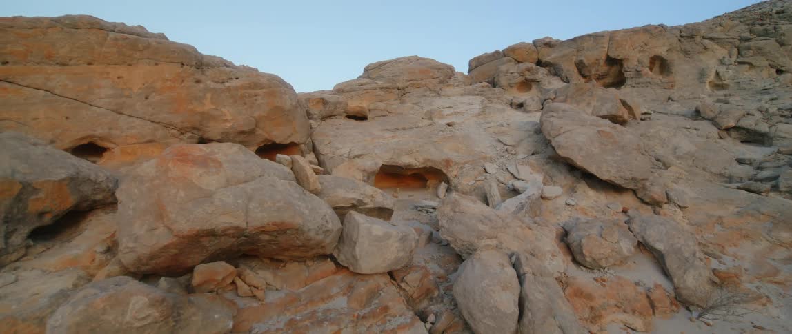 A rock covered mountain with many cave holes in the mountainside