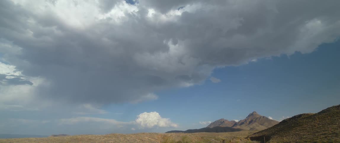 Dense and fluffy clouds fill the sky over a mountain range