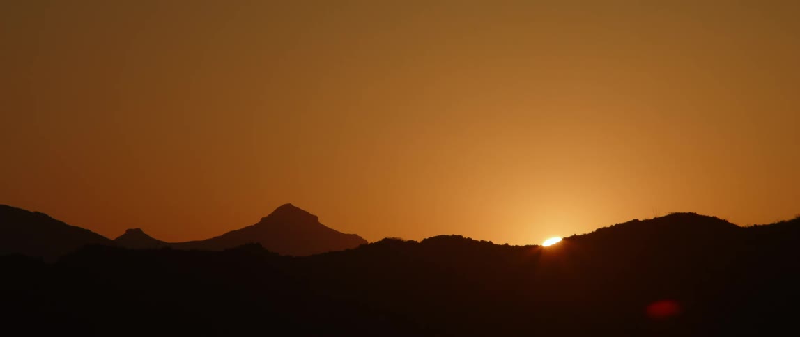 The sun setting behind hills