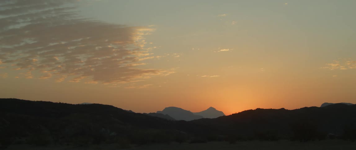 The sun sets over a mountain range