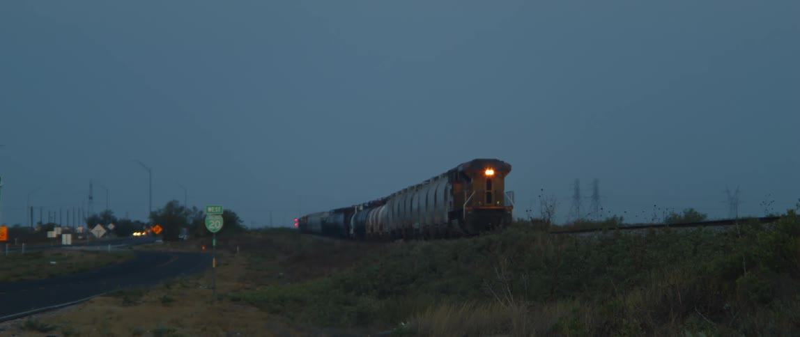 A freight train moves slowly on tracks toward an intersection