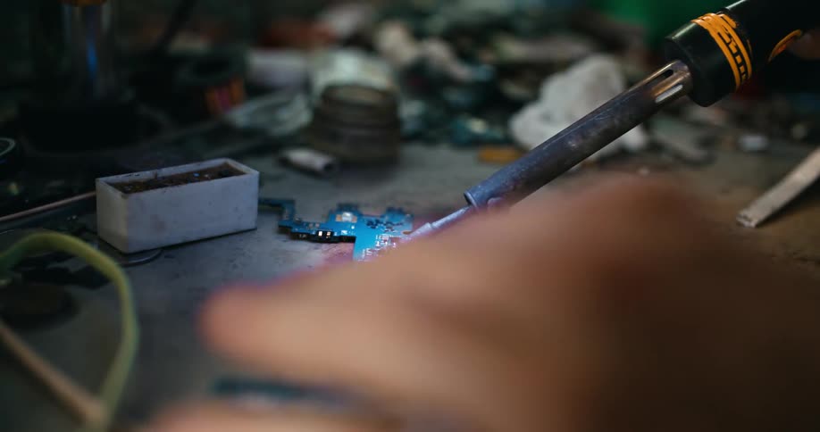 Person solders narrow circuit board on work surface