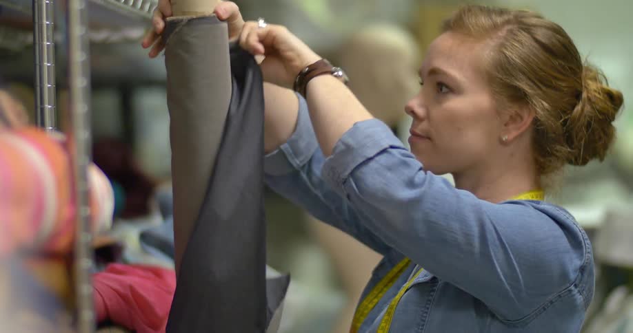 A woman rolls up fabric and puts it away