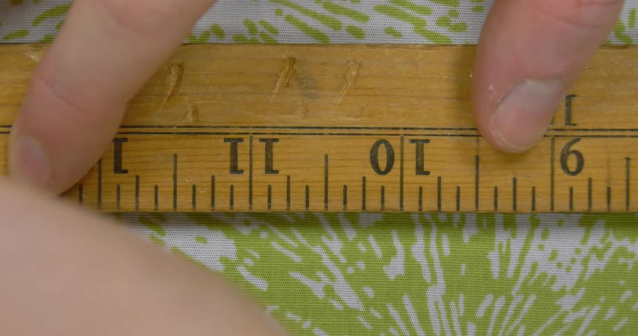 A wooden ruler is used to trace on fabric