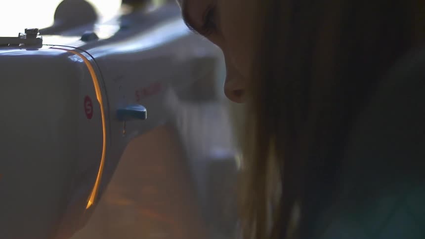 A woman is sewing fabric in a sewing machine
