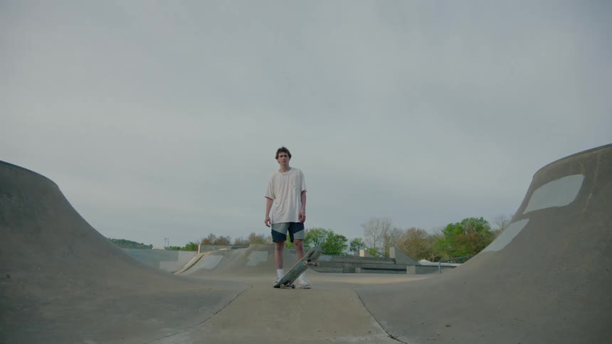 A wide portrait shot of a teenager skateboarder at a skatepark