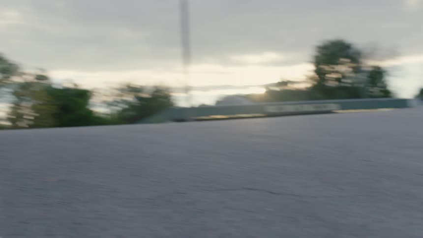 Two male skateboarders take jump as red tints horizon in the background